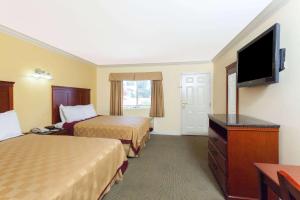 a hotel room with two beds and a flat screen tv at Travelodge by Wyndham Brea in Brea