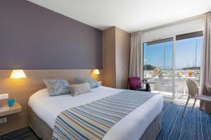 サン・ラファエルにあるBest Western Plus La Marinaのベッドとバルコニー付きのホテルルーム