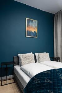 two beds in a room with a blue wall at RentPlanet - Apartament Piłsudskiego in Wrocław