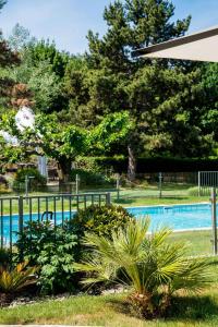 a swimming pool with a fence and some plants at Best Western Plus Clos Syrah in Valence