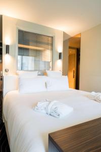 ein Schlafzimmer mit einem großen weißen Bett mit Handtüchern darauf in der Unterkunft Best Western Plus Clos Syrah in Valence