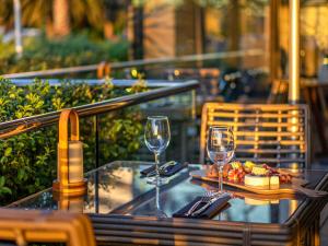 a table with two wine glasses and a plate of food at Pullman Vina del Mar San Martin in Viña del Mar