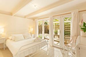 a white bedroom with a bed and a balcony at Kilara Cottage 3-Bed 2-Bath in Cowes
