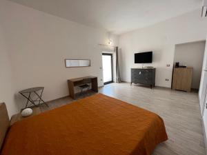 um quarto com uma cama, uma secretária e uma televisão em Residenza Giulia em Scanzano Jonico