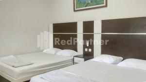 two beds in a room with white sheets at The SO Hotel Mitra RedDoorz in Pangandaran