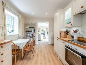 a kitchen with white cabinets and a table and chairs at The Coach House in Ingoldsby