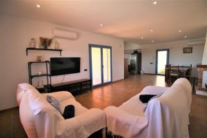 a living room with two white chairs and a flat screen tv at RA694 Casa con piscina de 4 dormitorios in Cuevas del Almanzora