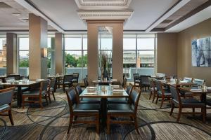 uma sala de jantar com mesas, cadeiras e janelas em Hilton Kansas City Country Club Plaza em Kansas City