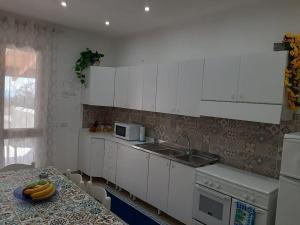 a kitchen with white cabinets and a sink and a table at Casa vacanze Gemini in Triscina