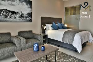 a bedroom with a bed and a couch and a table at Menlyn Maine Luxury Rentals in Pretoria