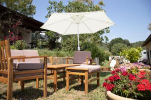 a patio table and chairs with an umbrella and flowers at Agriturismo Morani in Santa Severa