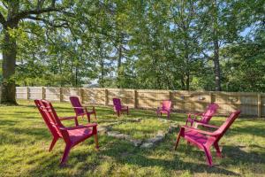 a group of red chairs sitting in the grass at Old Church Retreat with Fire Pit and Air Hockey! in Omaha