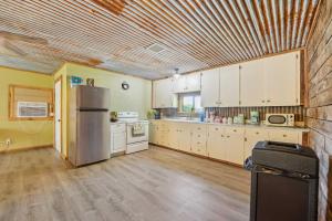 a kitchen with white cabinets and a stainless steel refrigerator at Old Church Retreat with Fire Pit and Air Hockey! in Omaha