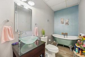 a bathroom with a sink and a tub and a toilet at Old Church Retreat with Fire Pit and Air Hockey! in Omaha +16 photos