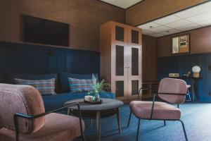 a living room with a blue couch and two chairs at Tweed Hotell Skaftö in Fiskebäckskil