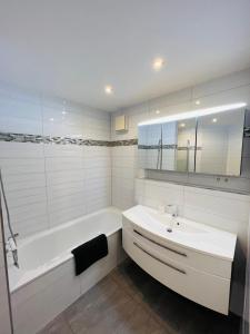 un bagno con vasca bianca, lavandino e vasca tubermott di Apartment Künzelsau a Künzelsau