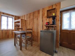 a kitchen with a table and chairs and a table and a refrigerator at Gîte du p'tit randonneur in Verrières-en-Forez