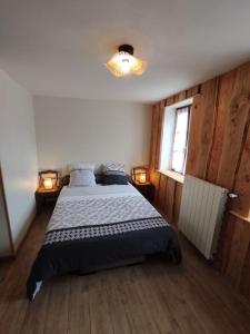 a bedroom with a bed and two lights and a window at Gîte du p'tit randonneur in Verrières-en-Forez