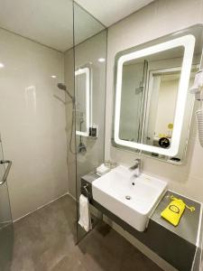 uma casa de banho com um lavatório, um chuveiro e um espelho. em YELLO Hotel Paskal Bandung em Bandung