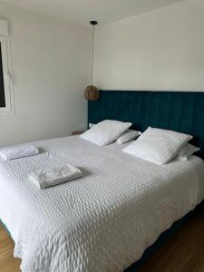 a large white bed with two pillows on it at maison avec piscine in Guéthary