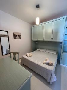 a bedroom with two beds and a table and cabinets at Appartamento Veronese in Olbia