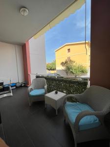 einen Balkon mit Stühlen, einem Tisch und einem Fenster in der Unterkunft Appartamento Veronese in Olbia