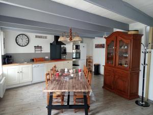uma cozinha com uma mesa com cadeiras e um relógio na parede em Gîte Ty Rest à 8 mn de la plage em Brengovel