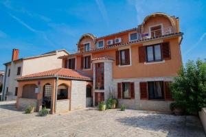 a large orange building with a roof at Rudel Room with Terrace in Fažana