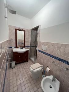ein Badezimmer mit einem Waschbecken, einem WC und einem Spiegel in der Unterkunft Appartamento Veronese in Olbia