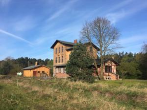 ein altes Haus auf einem Feld mit einem Baum in der Unterkunft Romantisches Studio am Waldesrand mit Gartensauna in Schwarz