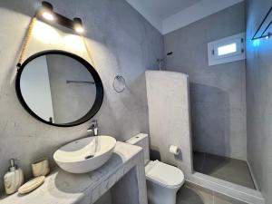 a bathroom with a sink and a mirror and a toilet at Family Villages Santorini in Vlychada Beach