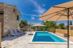 a pool with an umbrella and chairs next to a house at Holiday house EDEN in Rasopasno