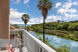 a balcony with a view of a river and palm trees at Flat just 280 m from the beach in Can Picafort
