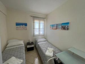 1 dormitorio con 2 camas, escritorio y ventana en Appartamento vista Mare [Il Principe] Free Parking, en Santa Maria del Focallo