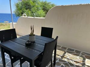 un tavolo nero con sedie e una pianta in vaso su un patio di Syra nest private beach a Liaropá