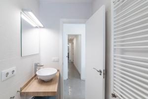 ein weißes Badezimmer mit einem Waschbecken und einem Spiegel in der Unterkunft AlohaMundi Corral del Rey in Sevilla