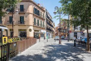 eine Stadtstraße mit einem Zaun und einem Gebäude in der Unterkunft AlohaMundi Corral del Rey in Sevilla