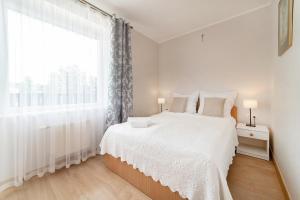 a white bedroom with a bed and a large window at Nord Jastarnia bis in Jastarnia