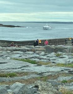 a group of people standing on the rocks with a boat in the water at New studio near Lahinch, Doolin & Cliffs of Moher in Lahinch