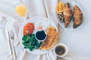 due piatti di prodotti per la colazione su un tavolo con succo d'arancia di Pharia Hotel and Apartments - by the beach a Hvar