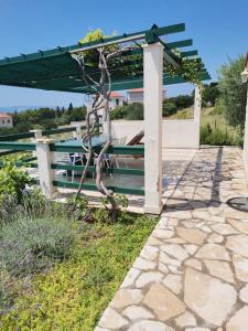 een pergola met een tafel en een bank bij Holiday Home Vineyard house in Bol