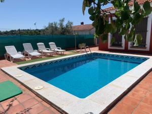 - une piscine avec 2 chaises longues dans l'établissement Casa situada en un entorno natural Casa Rural La Serena, à Trujillo