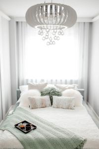 a white bedroom with a large bed with a chandelier at Apartament Staszica Nowa Sól in Nowa Sól