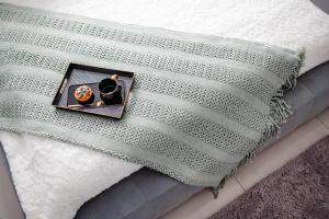 a bed with a white blanket with a plate on it at Apartament Staszica Nowa Sól in Nowa Sól