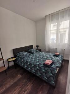 um quarto com uma cama com um edredão verde e uma janela em Très bel appartement climatisé à deux pas de la cathédrale em Reims