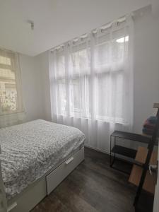 a white bedroom with a bed and a window at Très bel appartement climatisé à deux pas de la cathédrale in Reims