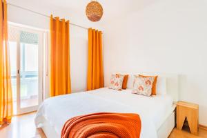 1 dormitorio con 1 cama con cortina naranja en Santo Amaro Beach Family Stays en Oeiras