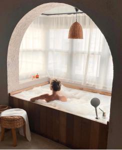 a person in a bath tub with a window at GAIA Alaçatı Bazaar in Alacati