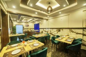 a restaurant with wooden tables and green chairs at SM Royal Suites - Hotel near Kempegowda international Airport Bangalore in Devanahalli-Bangalore