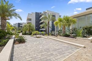 a walkway with palm trees in front of a building at 019 Green Hills Apartamento Exclusivo in Campoamor